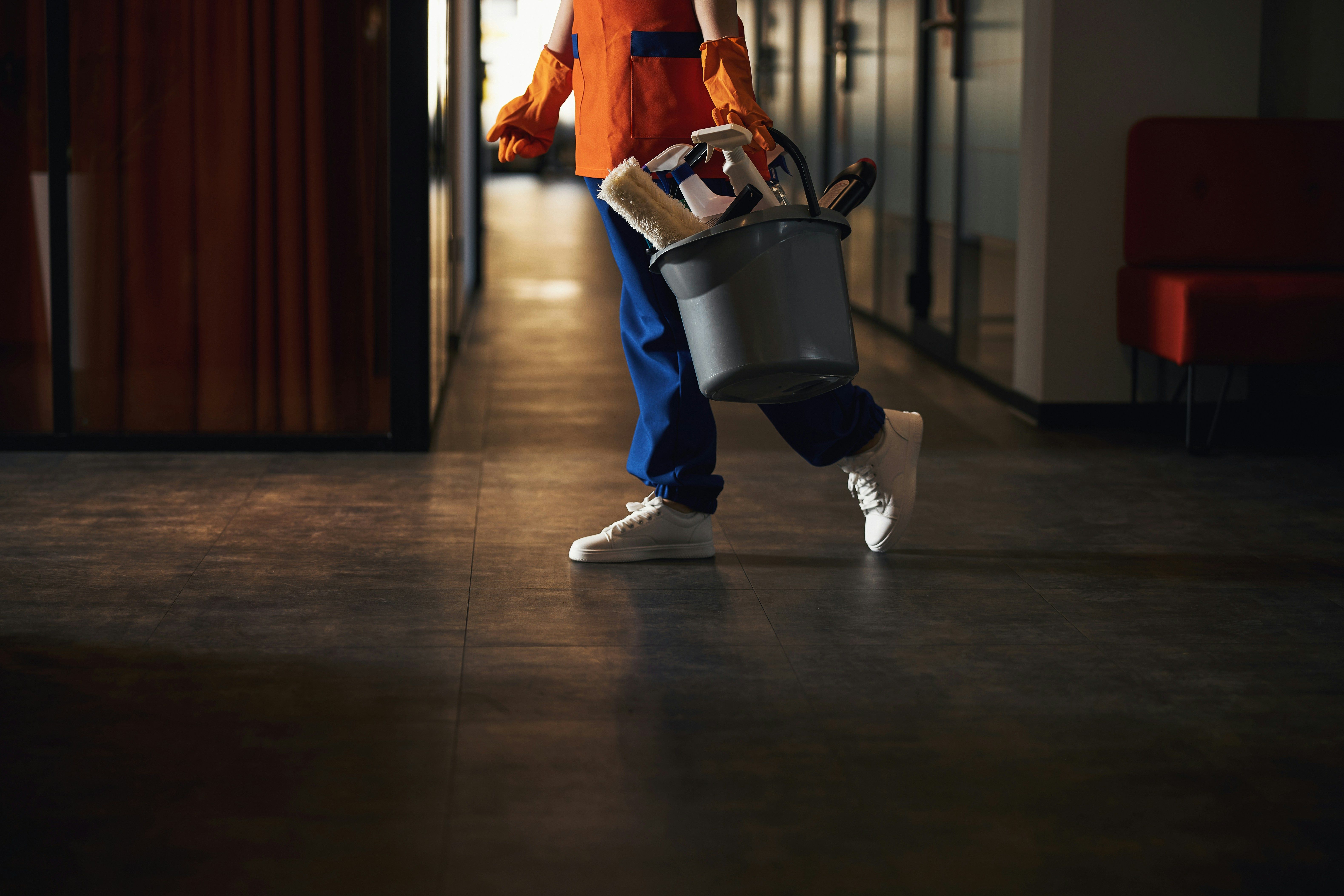 Janitor carrying bucket of supplies